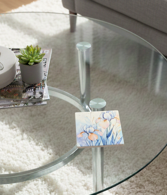 Square coaster with blue and orange iris watercolour art on a glass table next to a succulent in a grey pot.