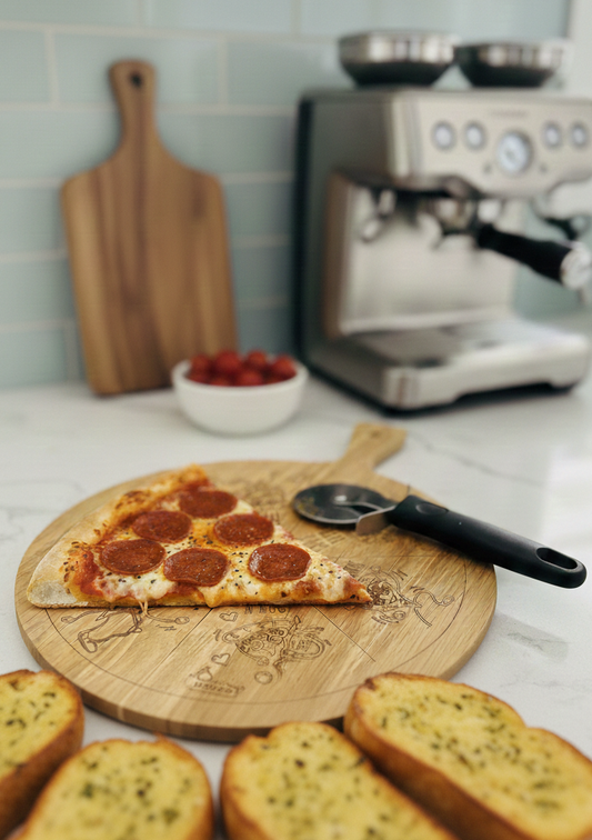 Warm pepperoni pizza slice and golden garlic bread on an engraved round wooden board. Kitchen counter setting, blue tiled backsplash.