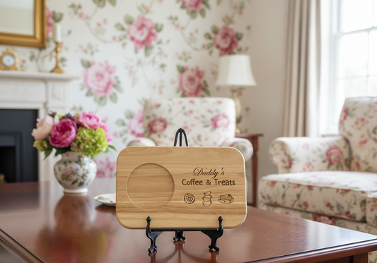 Light wood serving board on a black metal stand, displayed against pink and cream floral patterned wallpaper.