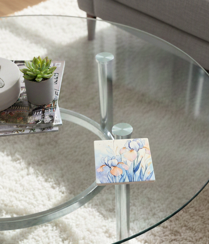 Square coaster with blue and orange iris watercolour art on a glass table next to a succulent in a grey pot.