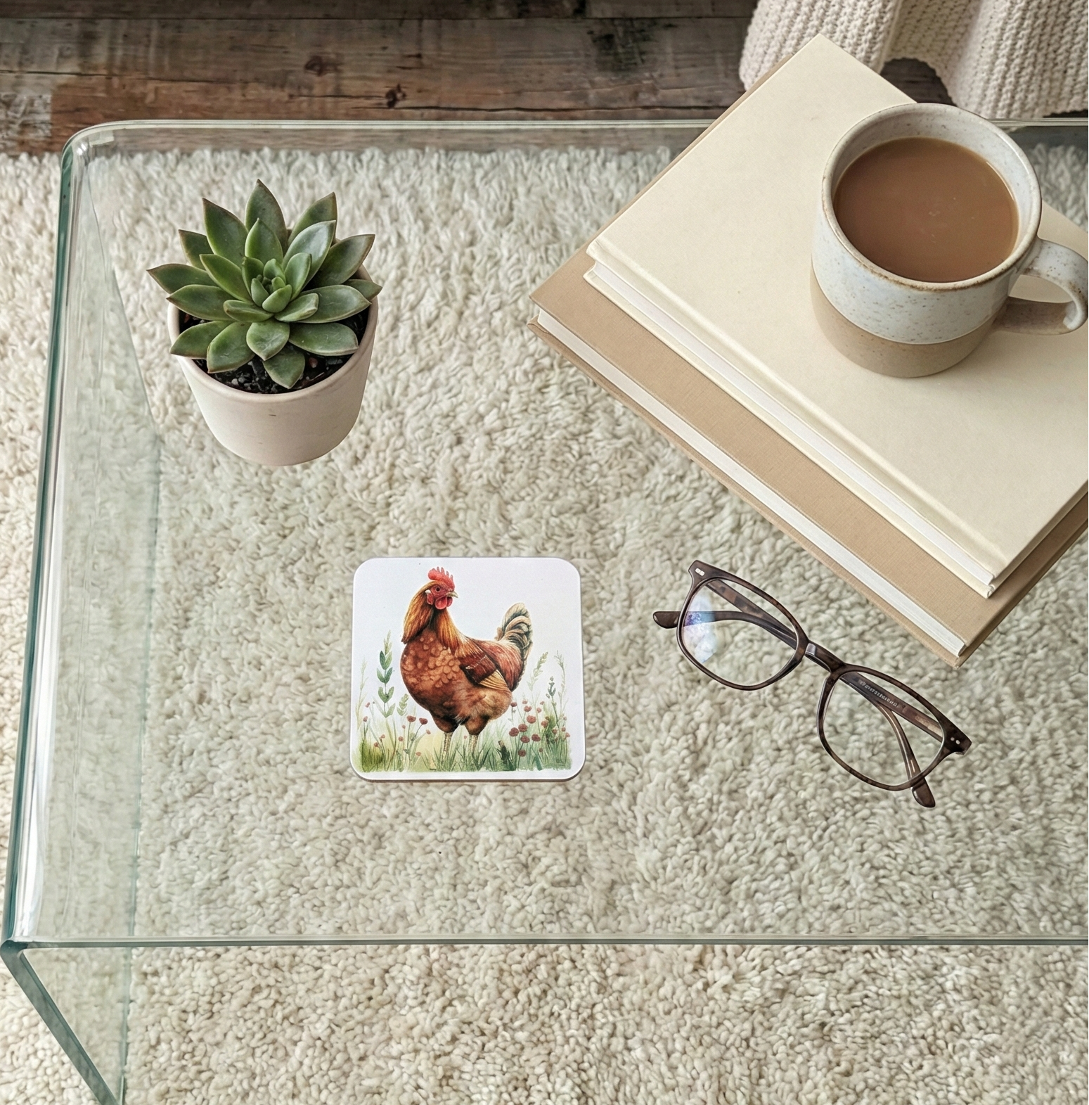 A square coaster illustrating a deep reddish-brown chicken standing amongst green foliage on a clear glass coffee table.