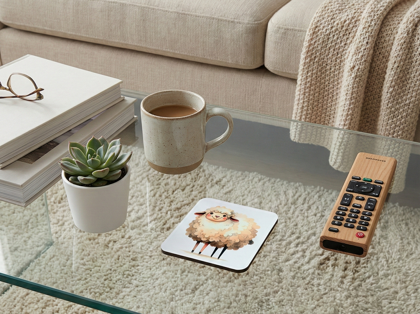 Square white coaster with a fluffy cream sheep on a glass table beside a speckled mug and light-wood remote.