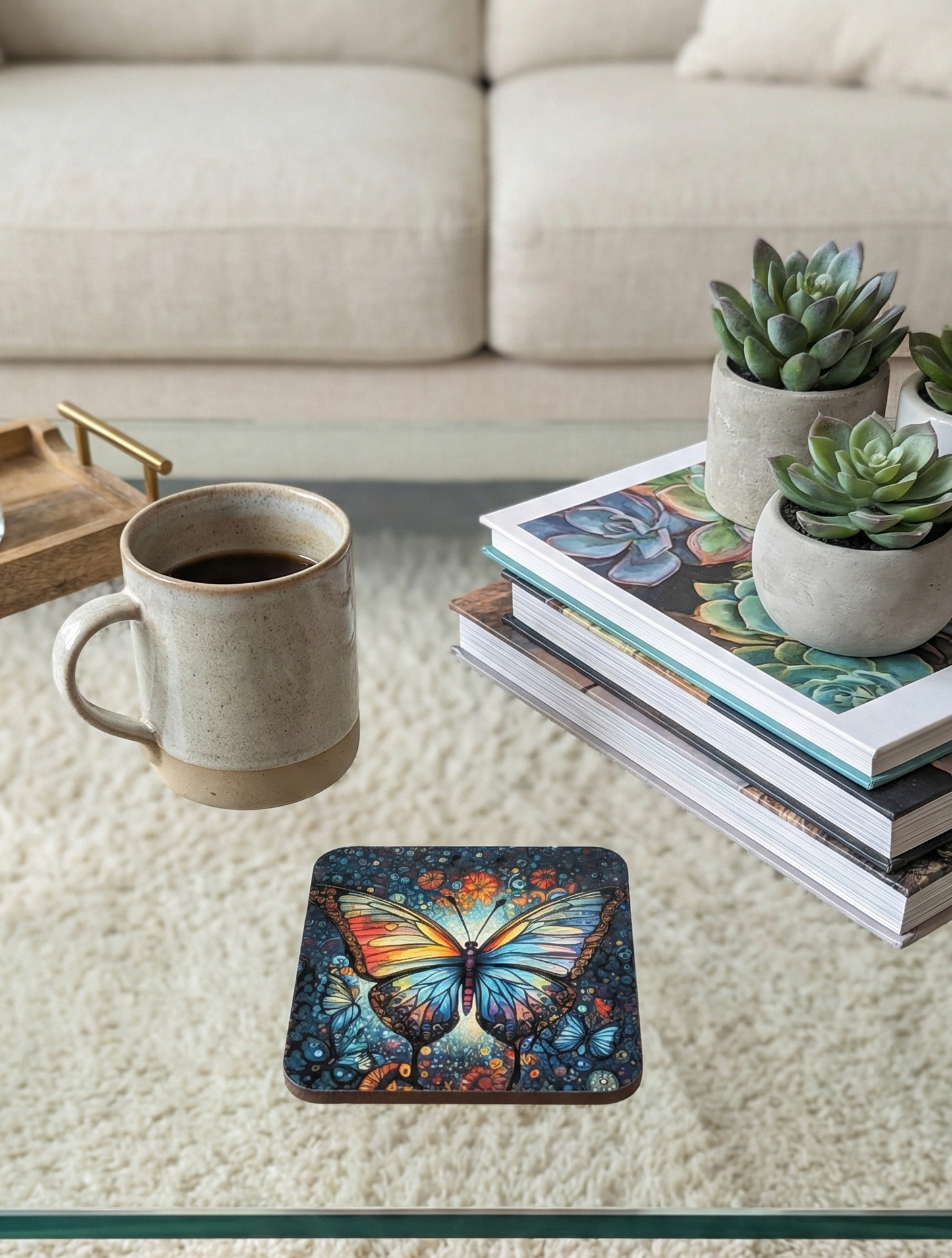 A highly detailed, square butterfly coaster appears to float slightly above a glass table near a coffee mug and succulents.