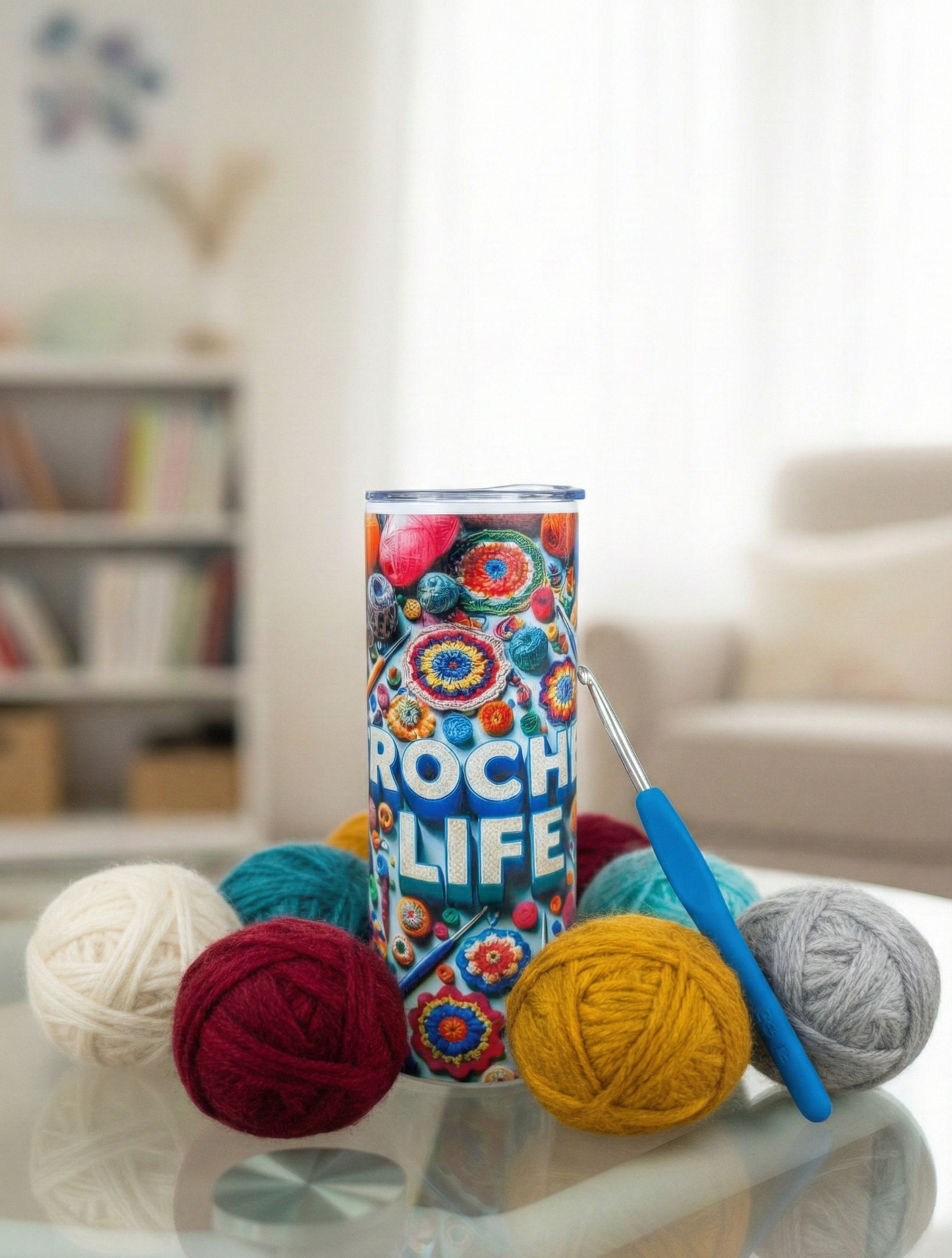 Vibrant 'Crochet Life' tumbler with balls of textured wool in mustard, teal and grey, beside a blue crochet hook.