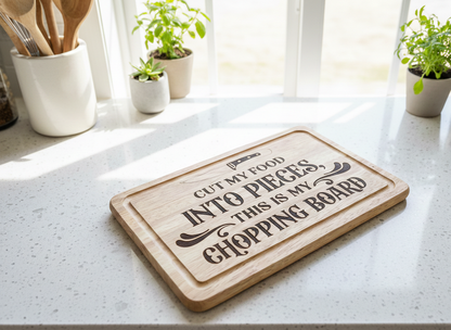 A light wood chopping board with bold black printed text sits on a speckled white quartz countertop in bright sunlight.