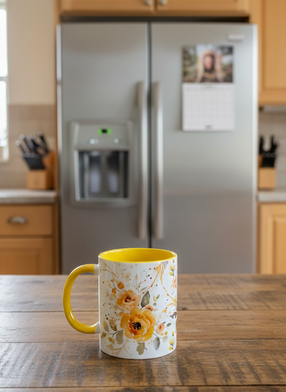 White floral mug with bright yellow interior and handle, resting on a dark, textured wood table. A blurred Grey fridge is behind.