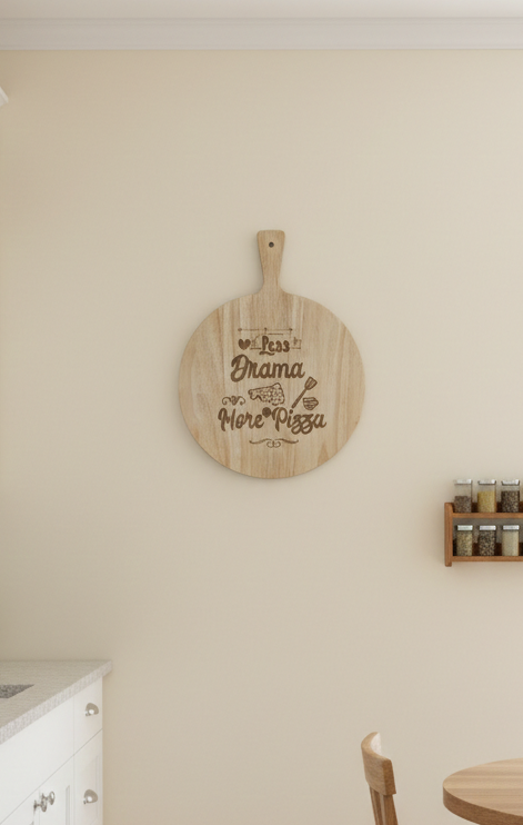 Pale Colour kitchen, white cabinetry, and light wood flooring. A round, engraved wooden pizza paddle hangs on the wall.