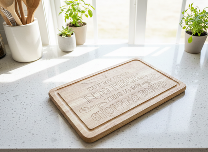 Bright daylight illuminates a light wood chopping board with engraved text, resting on a flecked white quartz counter.