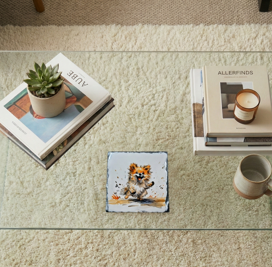 Slate coaster showing a fluffy ginger dog running, on a glass coffee table in a light-filled room.