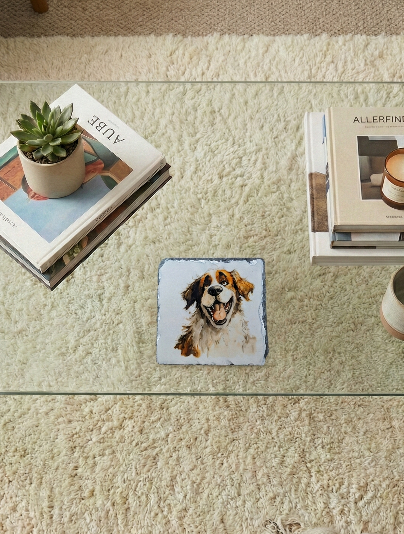 Square slate coaster with a large brown and white dog face, on a glass table over a cream textured rug.