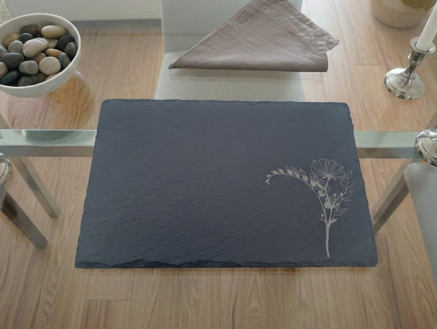 Textured charcoal slate placemat with a finely engraved white flower bunch in the bottom right-hand corner.