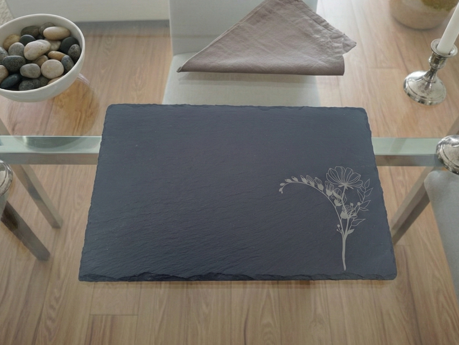 Textured charcoal slate placemat with a finely engraved white flower bunch in the bottom right-hand corner.