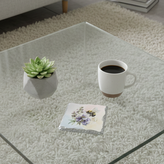 Stone coaster with a bee over purple watercolour flowers on a glass table with a green succulent and coffee mug.