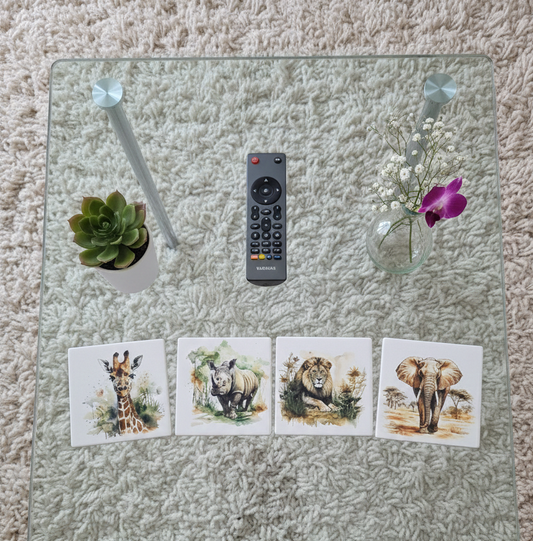 Four white animal-themed coasters on a glass table over a cream shaggy rug, with a succulent, remote, and flowers.