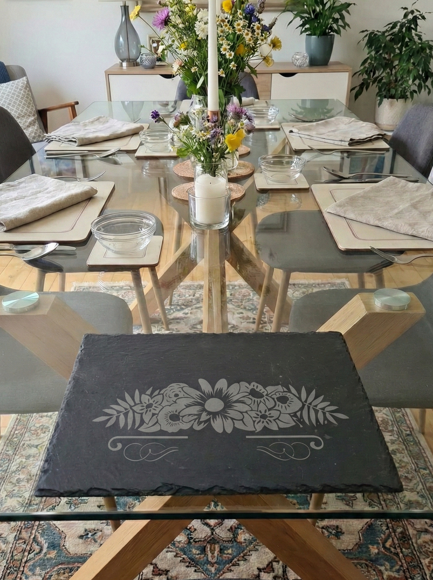 Slate placemat with a detailed floral bouquet engraving, part of a modern dining room table setting.