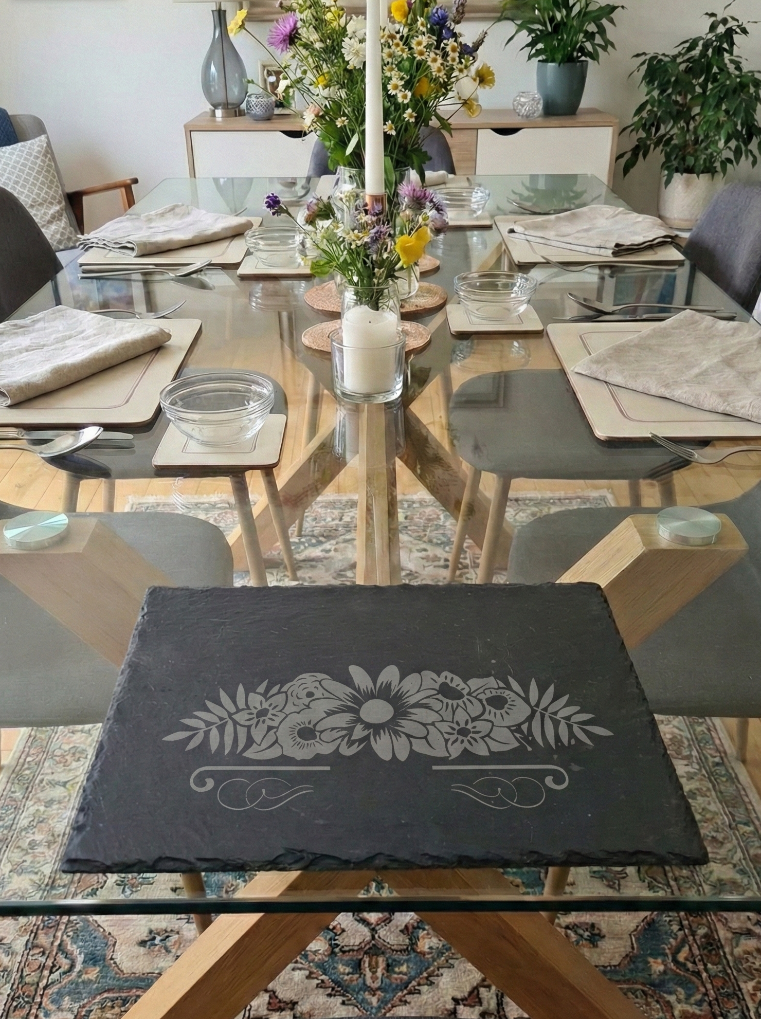 Slate placemat with a detailed floral bouquet engraving, part of a modern dining room table setting.