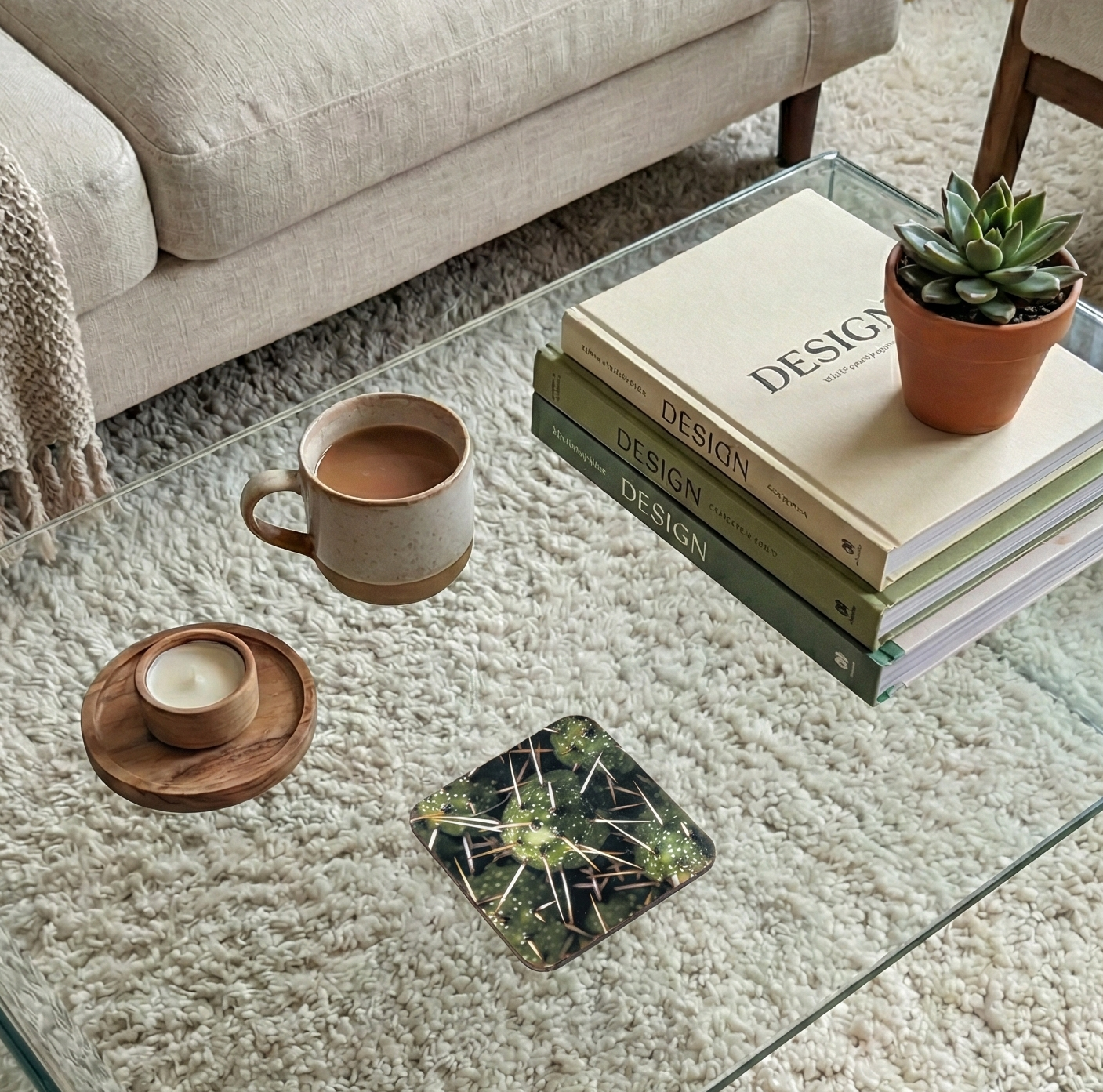 A square coaster featuring a dark green cactus detail crossed with long, prominent white spines on a clear glass table.