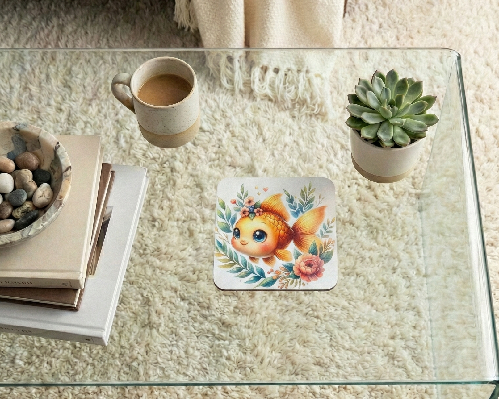 Square coaster with a cute orange goldfish illustration with large eyes, surrounded by green leaves and pink flowers.
