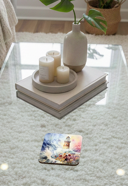 A square coaster featuring a serene lighthouse painting rests on a glass table under cream candles and a beige vase.