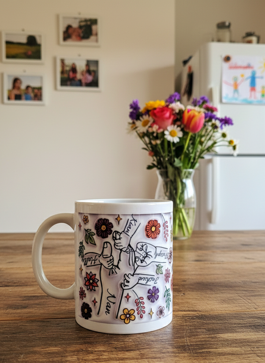 White ceramic mug with colourful floral illustrations and black line art of connecting hands, placed on a textured brown wooden table.