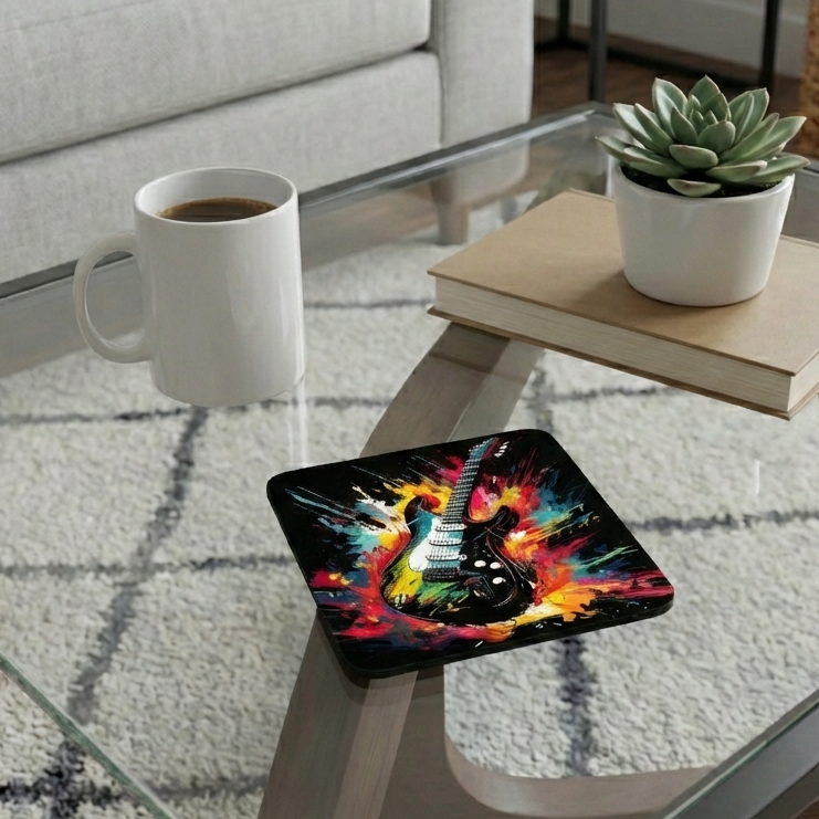 A guitar art coaster on a glass table next to a white mug and a small succulent plant sitting on a book.