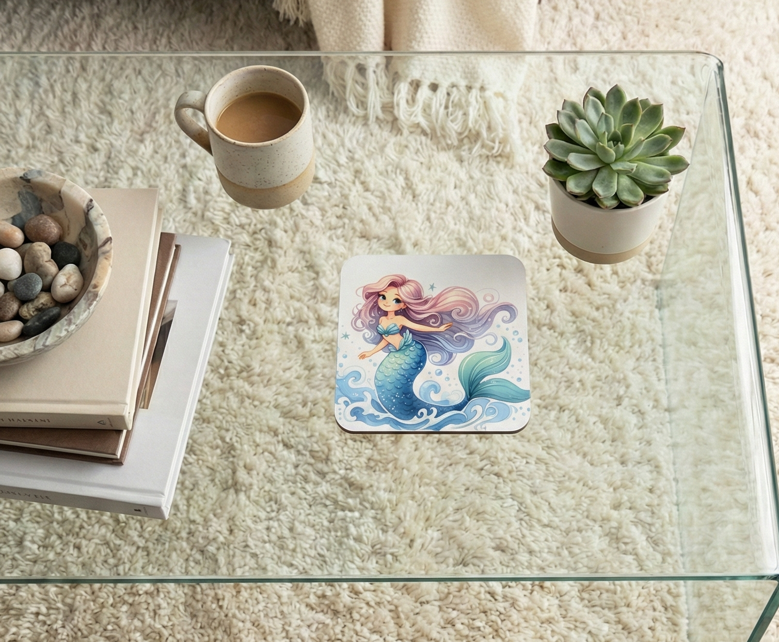 A square coaster with a colourful mermaid illustration with long purple hair and a blue tail, on a glass table top.