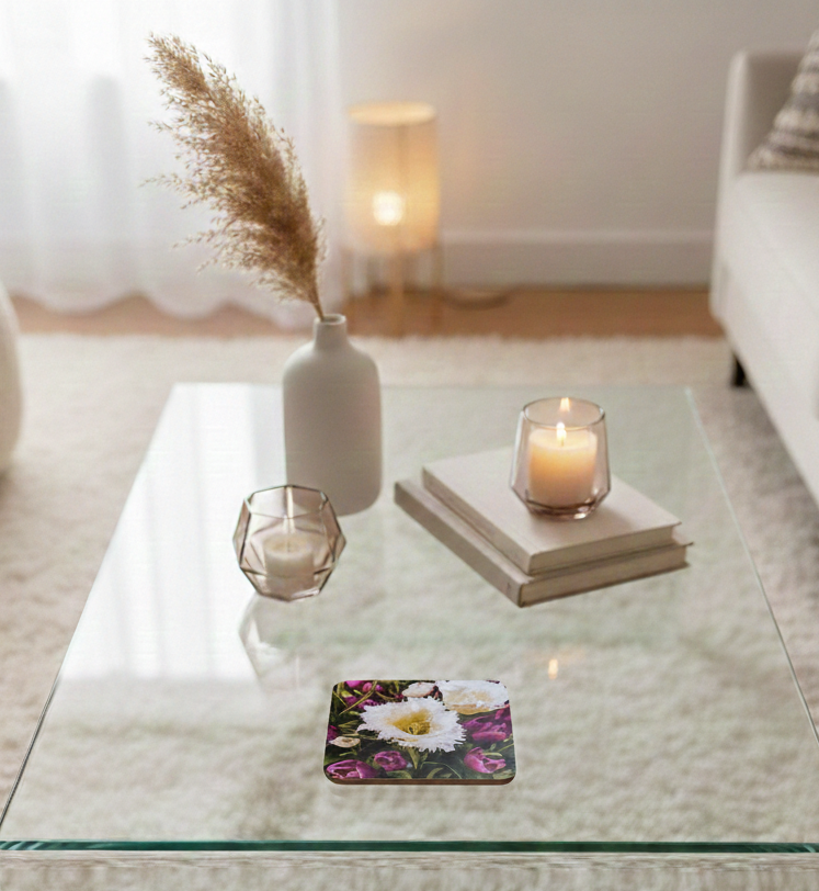 Square coaster with a purple and white floral pattern on a glass coffee table in a bright, neutral room.